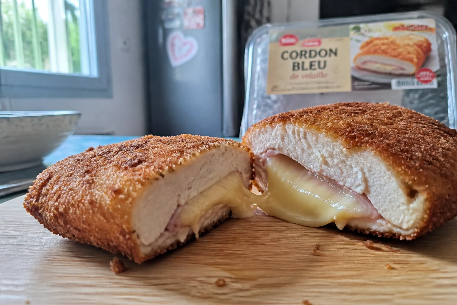 Cordon bleu de volaille coupé en deux montrant le fromage fondant, posé sur une planche en bois