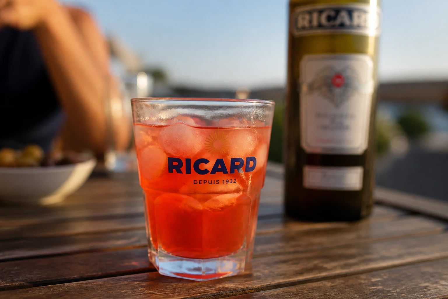 Verre de ricard grenadine coloré en rouge orangé servi en apéritif sur une table extérieure