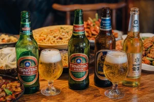 Bouteilles de bières chinoises Tsingtao et Snow servies dans des verres avec plats de cuisine chinoise